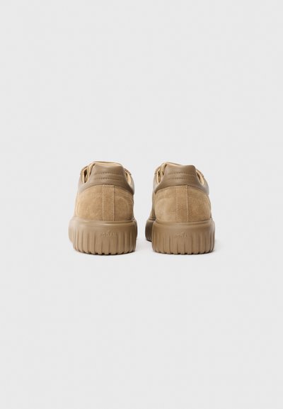 Pair of tan suede sneakers with thick rubber soles, viewed from the back on a plain white background.
