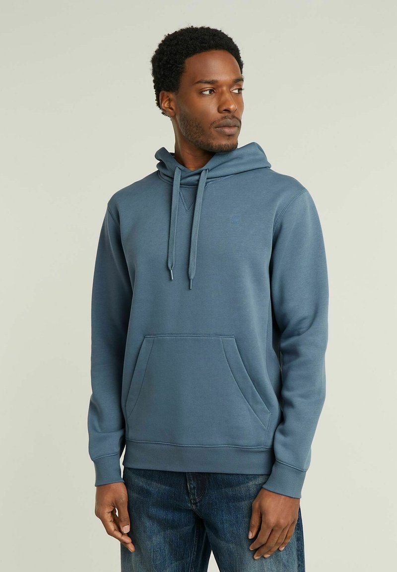 Felpa blu in cotone con tasca a marsupio, cappuccio regolabile con cordini, polsini e fondo a costine. Design semplice con un piccolo logo sul petto.