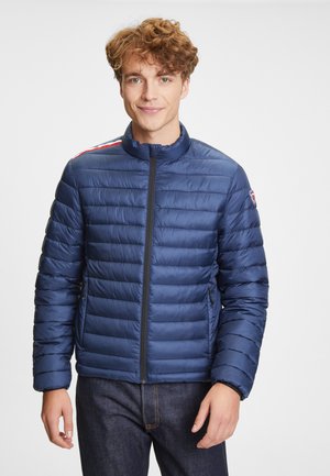 Marineblauer gesteppter Puffer-Jacke mit Stehkragen, frontalem Reißverschluss, Seitentaschen und roten sowie weißen Streifen auf den Schultern.