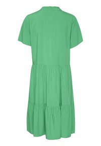 Rochie scurtă verde cu mâneci scurte, cu guler asimetrical și design în straturi. Țesătură netedă cu o formă în A, ajungând până la mijlocul coapsei. Fără modele sau accente.