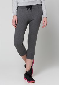 Pantalones de chándal cortos grises con una cintura elástica ajustable, fabricados en una suave tela y con puños acanalados. Combinados con zapatos negros con detalles rosas.