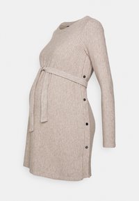 Schwangerschaftskleid aus weichem, beigem Rippstoff mit langen Ärmeln, verstellbarem Gürtel in der Taille und seitlichen Knöpfen für zusätzliche Details.