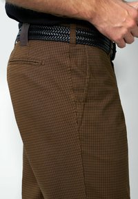 Bruine geruite broek met een rokerige afwerking, voorzien van een strak ontwerp, zijzak en een geweven zwarte leren riem.