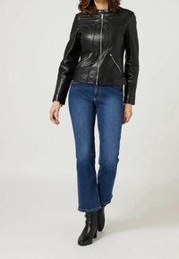 Svart skinnjacka med kviltade detaljer, dragkedjefront och två sidofickor, i kombination med blå utsvängda jeans och svarta klackstövlar.