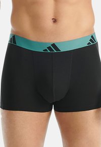 Černé boxerky s tyrkysově modrým elastickým pasem s černým logem. Hladká látka s přiléhavým střihem a plochými švy.