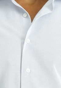 Camicetta a maniche corte a righe di colore azzurro chiaro, con colletto a bandiera, patta frontale con bottoni bianchi e una texture del tessuto liscia e morbida.