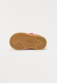 Semelle de chaussure Reebok, en caoutchouc avec un motif en nid d'abeille, dotée d'un dessus rose et d'une semelle extérieure en caoutchouc texturé marron avec détail du logo.