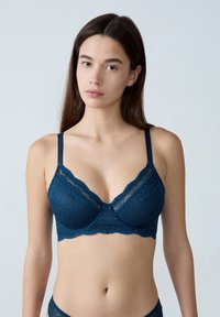 Granatowy koronkowy biustonosz braletka z falbaniastym brzegiem, trójkątnymi miseczkami, regulowanymi ramiączkami oraz geometrycznym wzorem.