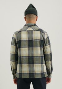Geverfd flanellen shirt in beige, groen en marineblauw met een button-down kraag; heeft lange mouwen en een rechte zoom. De textuur lijkt zacht.