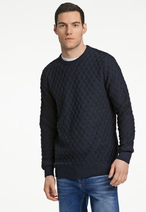 Marinenavysweater met een gestructureerd ruitpatroon, ronde hals en geribbelde manchetten en onderrand, gecombineerd met blauwe jeans. Duurzaam breiwerk.