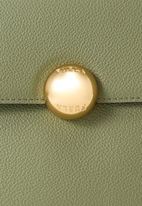 Πράσινο ανοιχτό πορτοφόλι από δέρμα, με επιβλητικό χρυσό κούμπωμα με ανάγλυφο λογότυπο "FURLA" και υφή στην επιφάνεια.