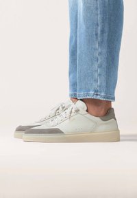 Sneakers in pelle bianca con accenti in suede grigi e suola in gomma beige. Presentano una chiusura con lacci e un dettaglio del logo sul lato.