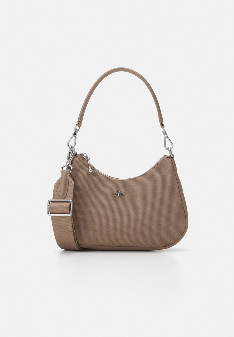 Sac à bandoulière taupe à la forme courbée, poignée courte, large sangle amovible, détails en métal argenté et petit logo sur le devant, sur fond blanc.