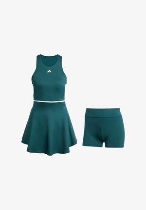 Two-piece athletic set in deep teal, featuring a fitted tank top and a flared skirt with built-in shorts. Smooth texture, white accent band.