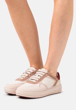Sneaker crema e beige con accenti in suede texture e tallone rosso a contrasto. Presentano lacci piatti e una suola spessa e imbottita.