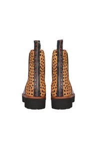 Braune Chelsea-Stiefel mit Punkten, schwarzen Lederakzenten, strukturiertem Finish, roten Nähten und Gummisohle. Rückansicht mit Zuglaschen.