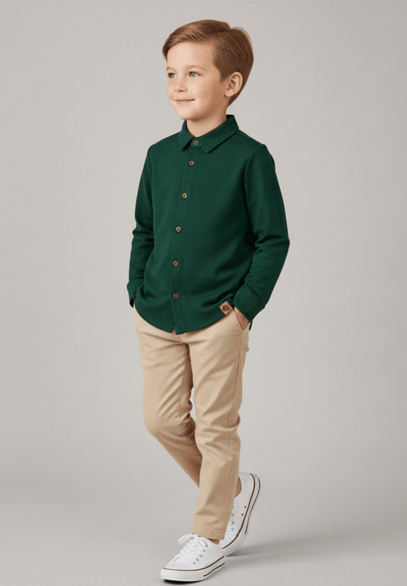 Zielona koszula z guzikami i kołnierzykiem, w połączeniu z beżowymi spodniami i białymi trampkami. Drewniane guziki i detal w postaci naszywki na koszuli.