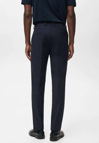 Pantalones de marino con un corte ajustado, que presentan bolsillos traseros, una textura suave y un diseño clásico. Combinados con zapatos negros.