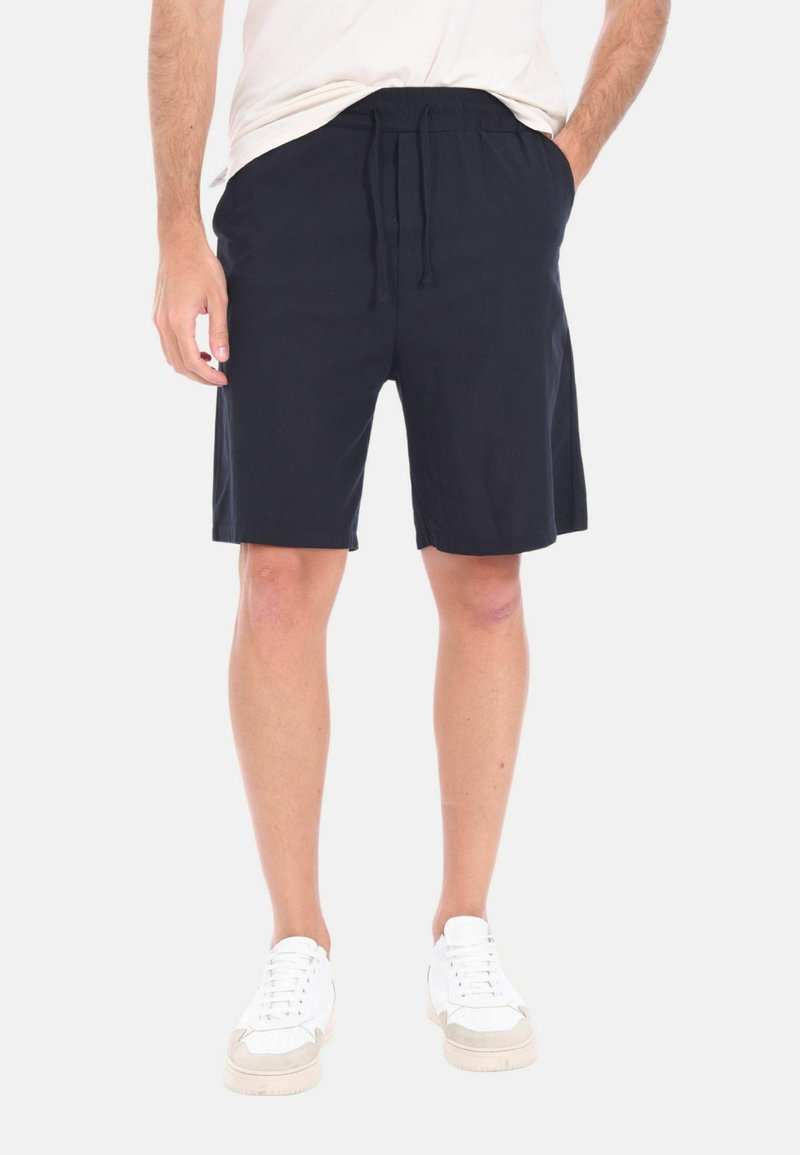 Pantaloni corti blu navy realizzati in tessuto morbido con vita elastica, cordoncino regolabile e due tasche laterali. Design con fronte piatto.