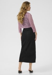 Lila csipkés, háromnegyedes ujjú cropped top, ívelt szegéllyel, párosítva egy magas derekú, fekete farmer szoknyával, amely a bokáig ér.