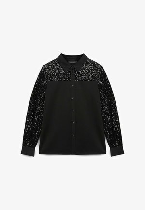 Czarna bluzka z kołnierzykiem i guziczkami z przodu, z cekinową czarną tkaniną na górnej części rękawów i ramionach. Miękki materiał, luźny krój.