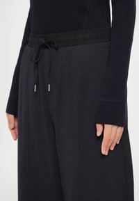 Donkergrijze sweatpants met een elastische tailleband, koordsluiting en zijzakken; textuurstof met een gladde afwerking.