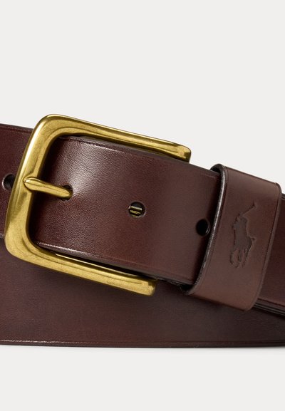 Καφέ δερμάτινη ζώνη με χρυσή ορθογώνια αγκράφα και ανάγλυφο λογότυπο παίκτη πόλο στη θηλιά της ζώνης, απεικονιζόμενη σε λευκό φόντο.