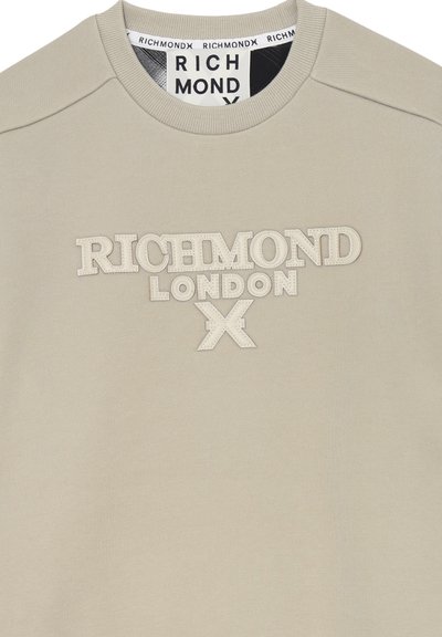 Felpa beige chiaro con colletto rotondo, caratterizzata da un logo in rilievo bianco sporco "RICHMOND LONDON" e un tessuto leggermente testurizzato.