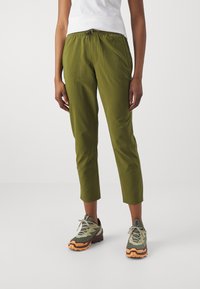 Světle olivové lehké kalhoty s elastickým pasem, zkrácenou délkou a postranními kapsami. V kombinaci se šedými a oranžovými turistickými botami.