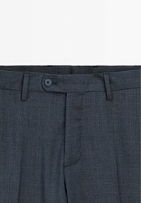 Charcoal gray trousers with a textured fabric, front pleats, and a single button closure. Features belt loops and side pockets.