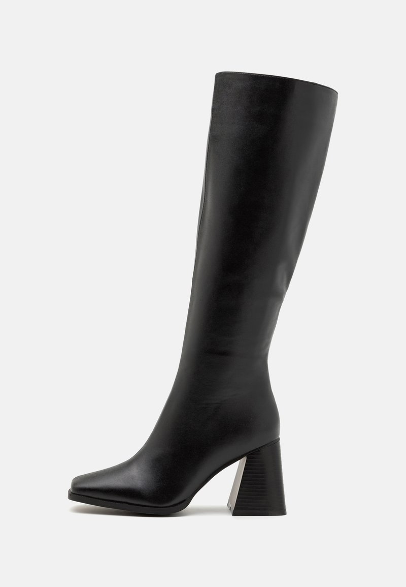 Black knee-high boot made of smooth leather, featuring a square toe and a chunky, textured heel. Simple and streamlined design.
