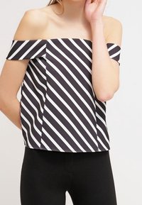 Off-the-shoulder topp med svart och vit snedställning, kort ärm och en strukturerad passform. Blandning av bomull med en slät yta.