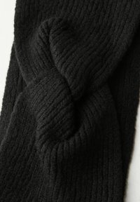 Diadema de punto negro hecha de un suave tejido acanalado, que presenta un diseño de nudo torcido en la parte delantera para un aspecto texturizado.