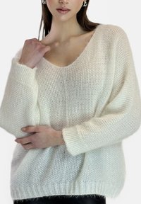 Oversized strikket sweater, off-white, med en dyb V-hals, ribbede ærmekanter og kant. Blødt, tekstureret stof med løse sømdetaljer.