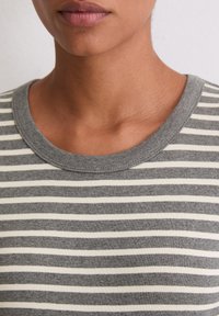 Szara i kremowa koszulka w paski z okrągłym dekoltem i miękką fakturą, z równomiernie rozmieszczonymi poziomymi liniami.