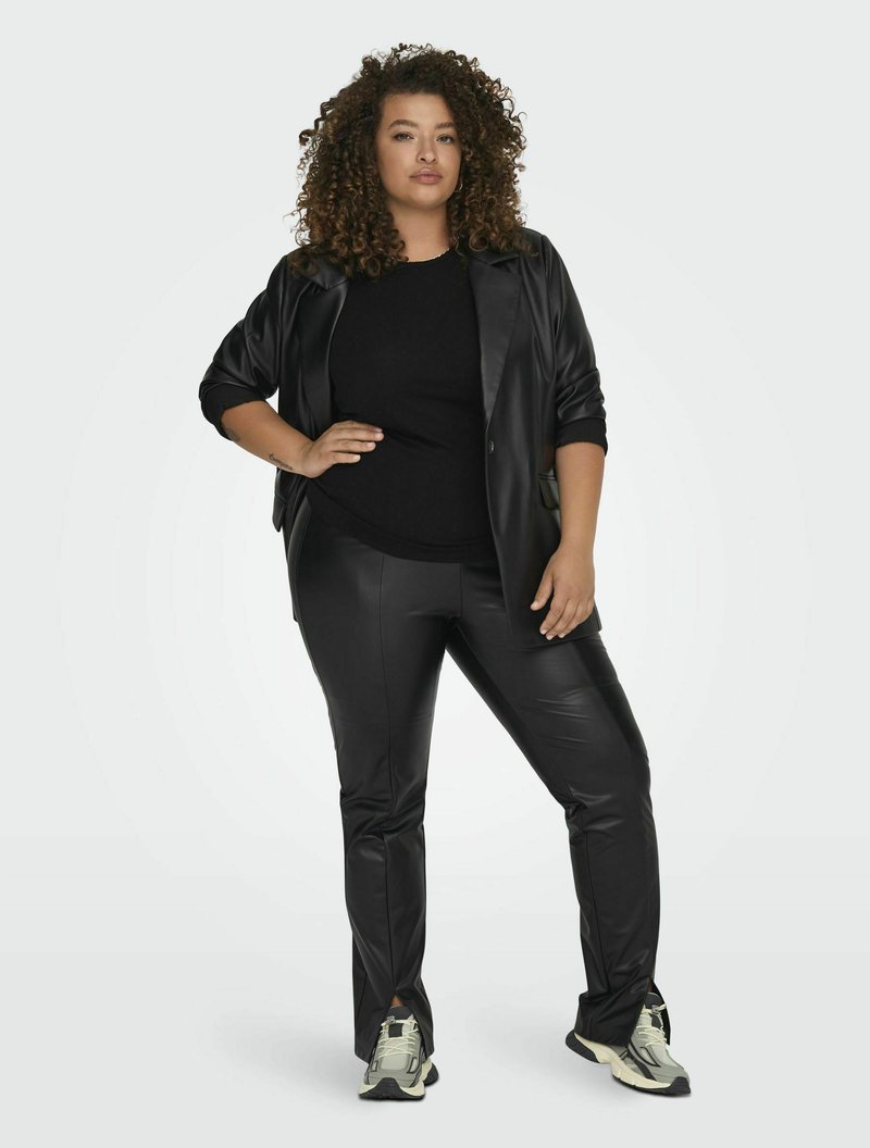 Zwarte neplederen blazer en bijpassende broek, gecombineerd met een zwart top en lichtgekleurde sneakers. Soepele textuur met een getailleerde pasvorm.