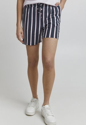 Shorts navy avec des rayures verticales roses et blanches, dotés d'une taille élastique et d'un cordon de serrage. Associés à des baskets blanches.