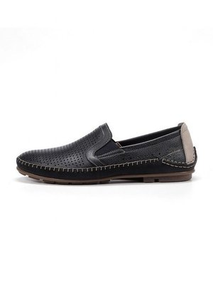 Zapatos negros sin cordones con parte superior de cuero perforado, tacón gris en contraste y detalle de costura beige a lo largo de la suela. Suela de goma plana.