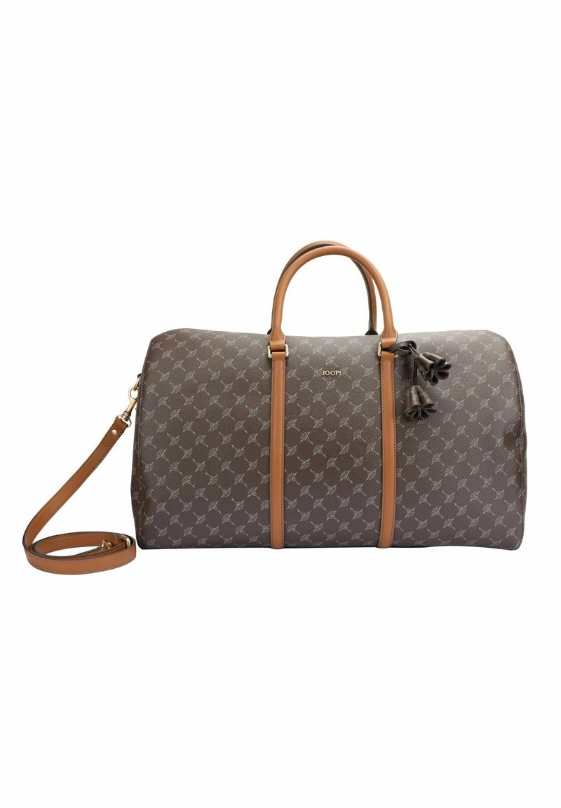 Ruskea kuvioitu duffel-laukku, jossa on vaaleanruskeat nahkakahvat ja irrotettava hihna. Koristeena tupsut ja pieni logo sivulla.