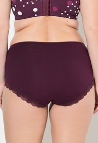 Bordó dámské kalhotky mají hladký materiál s vlnitým krajkovým lemem. Design obsahuje jednobarevný bez vzorů.