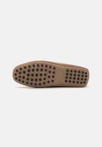 Suela de zapato de ante color marrón claro con un diseño liso y puntos de goma negra para mayor tracción, forma de puntera redondeada y perfil minimalista.