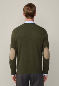 Olive green sweater with a crew neckline, textured fabric, and beige elbow patches. Features ribbed cuffs and hem. Minimalistic design.