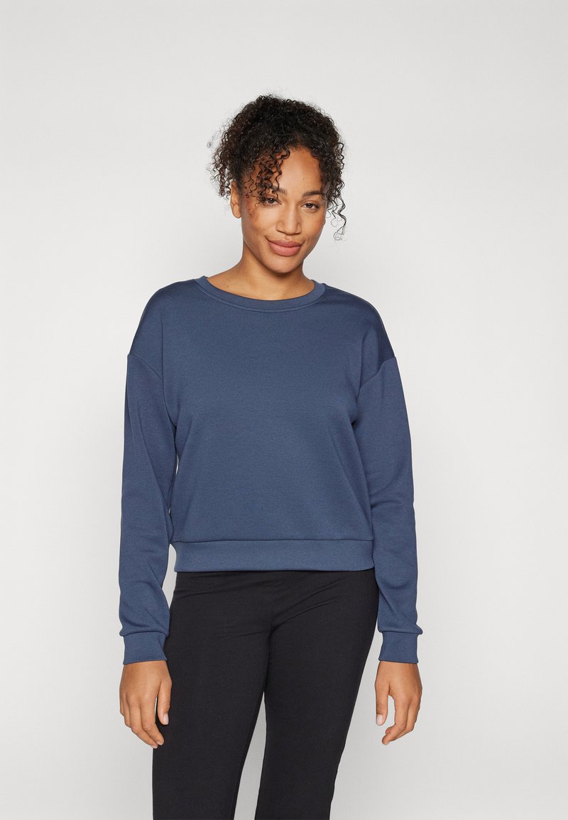 Felpa blu navy realizzata in morbido tessuto, con una vestibilità comoda, scollatura rotonda e polsini a costine. Abbinata a leggings neri.