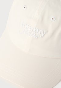 Καπέλο μπέιζμπολ κρεμ χρώματος με λευκό κεντημένο λογότυπο "tommy jeans" στο μπροστινό πάνελ και ραμμένες τρύπες αερισμού.