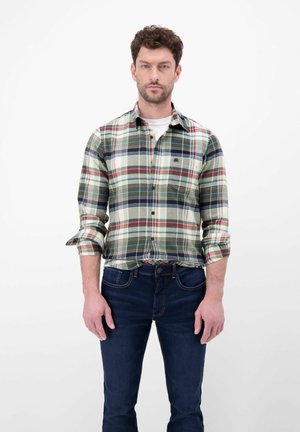 Grøn og cremefarvet ternet skjorte med røde og blå detaljer, knapkrave, opbøjede ærmer, båret med mørkeblå jeans. Glat stoftekstur.