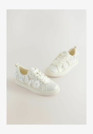 Adidași albi cu șireturi din satin, panou lateral sclipitor și ornamente florale aproape de călcâi. Partea superioară netedă și talpă texturată.