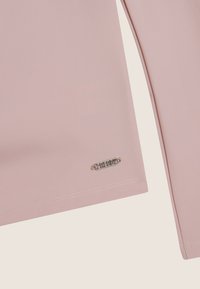 Top de manga larga rosa hecho de un material suave, con un logotipo de hardware plateado en el dobladillo y detalles de costura blanca en contraste.