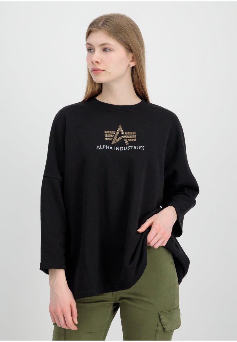 Schwarzer Sweatshirt mit lässigem Schnitt, ausgestattet mit einem goldenen und silbernen Logo "ALPHA INDUSTRIES" auf der Vorderseite und langen, weiten Ärmeln.