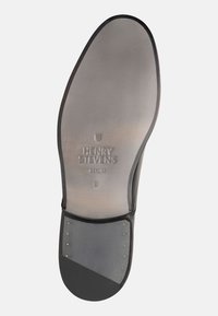 Schwarze Ledersohle mit glatter Oberfläche, geprägtem Logo "HENRY STEVENS BERLIN" und Metallnieten an der Ferse. Abgerundete Kanten.