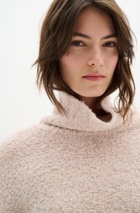 Maglione rosa, strutturato, con colletto alto; tessuto morbido e peloso che mette in mostra un design a maglia larga; aspetto caldo e accogliente.